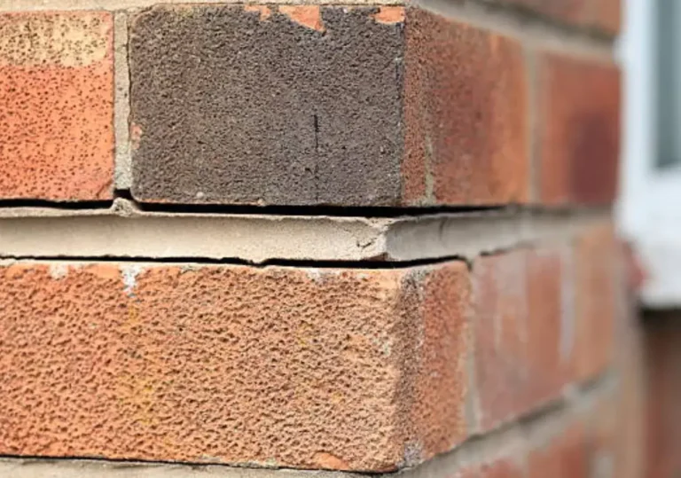 Close-up of cracked brickwork and separated mortar joints on an exterior wall, indicating possible structural movement or foundation settlement damage.